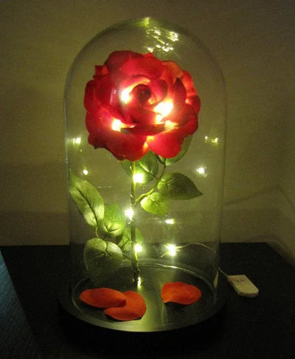 LED glass dome rose lamp with red flower, green leaves, and scattered petals
