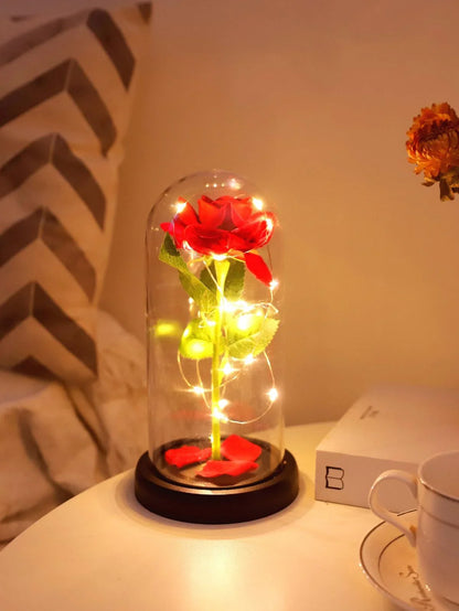 Red rose in glass dome with LED fairy lights on nightstand, cozy decor