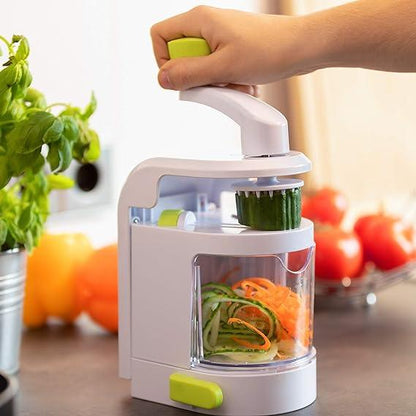 Hand using a vegetable spiralizer slicer for zucchini and carrots in a kitchen setting