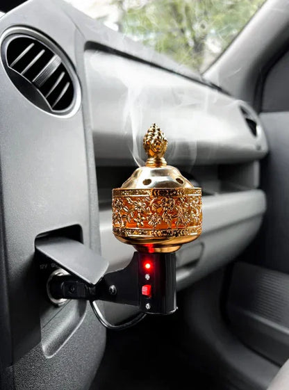 Decorative gold electric incense burner plugged into a car vent with visible smoke.